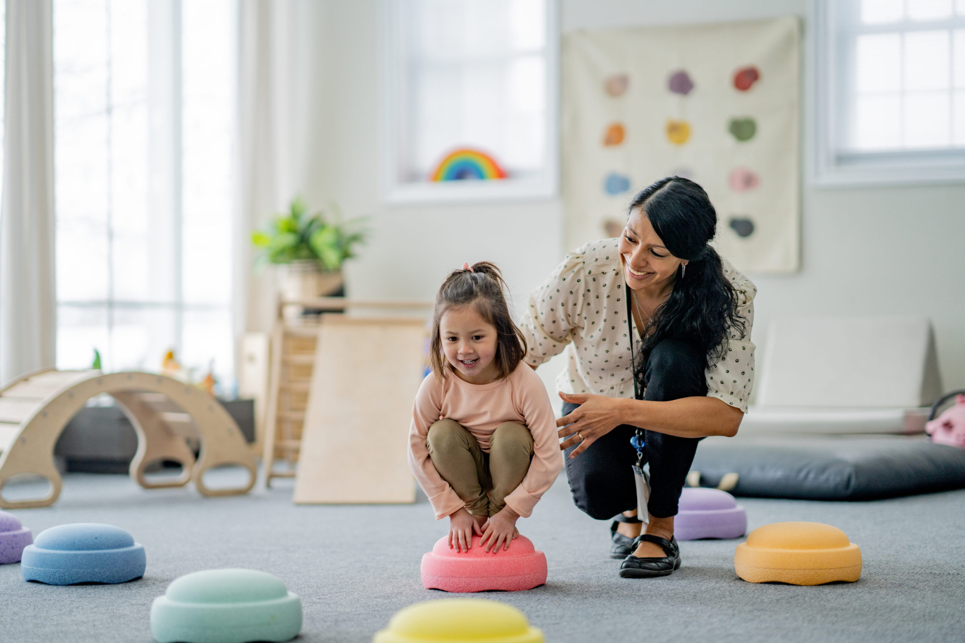 Child engaging in playful early intervention session with supportive therapist.